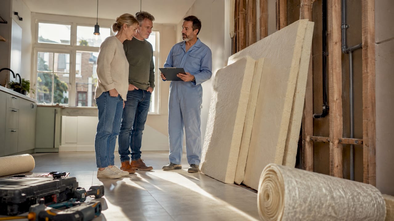Een stel bekijkt samen met de aannemer het uitgevoerde isolatiewerk in hun woning.