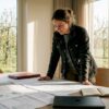 Een bouwspecialist kijkt kritisch naar de milieueisen en controleert of de bouwtekeningen hieraan voldoen.