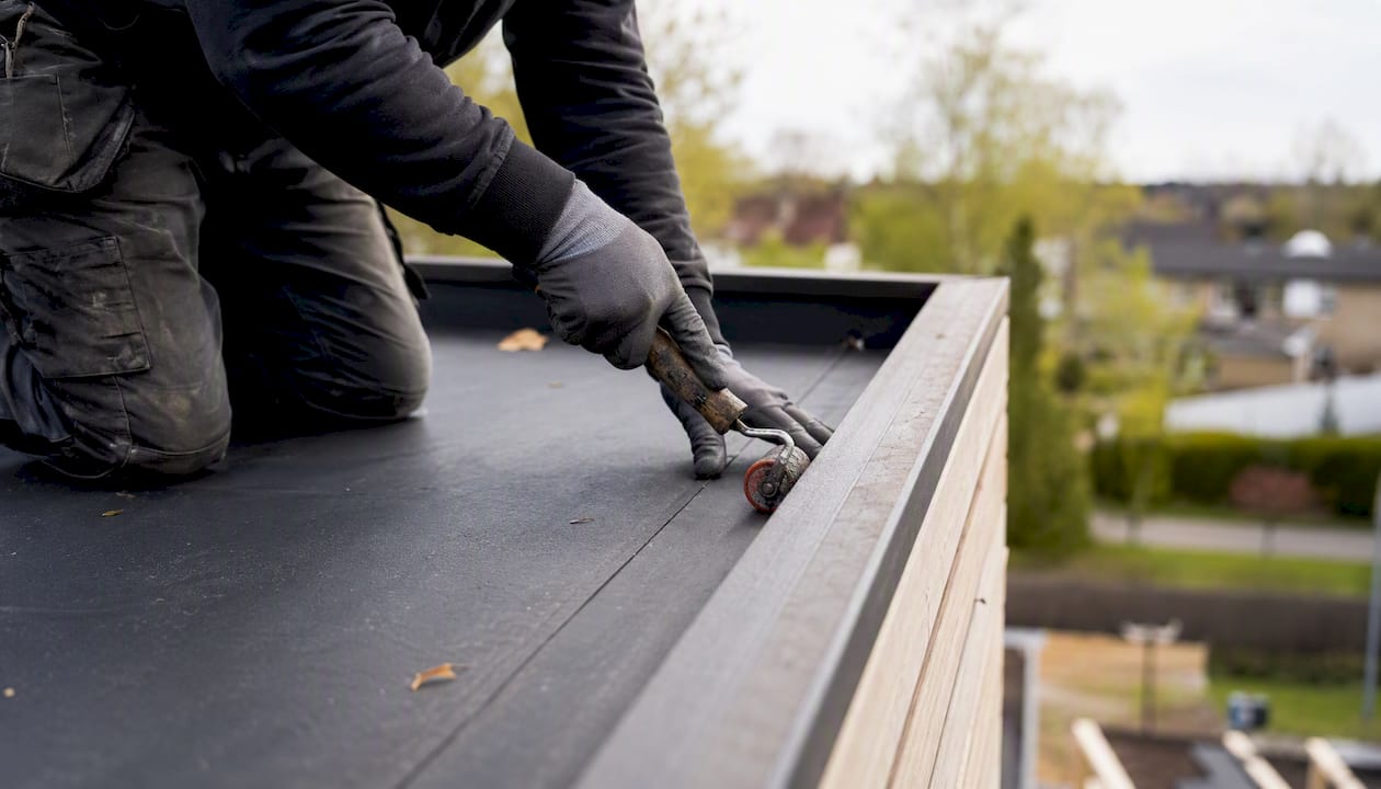 Met de handen wordt de EPDM-naad gladgestreken op het platte dak.