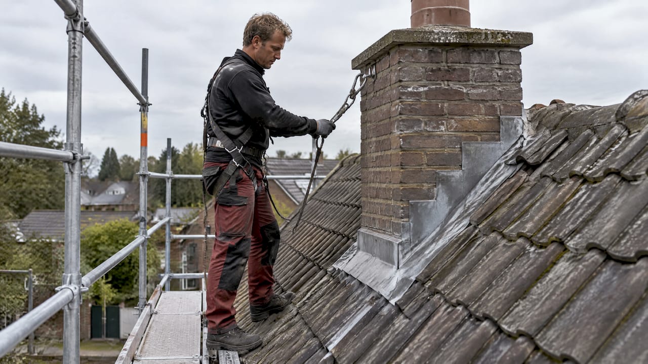 Dakwerker met valbeveiliging aan de schoorsteen
