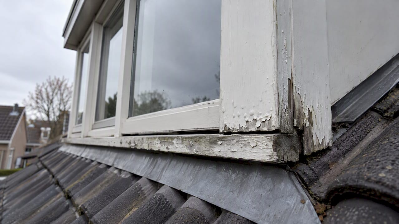 Bladderende verf aan de onderhoek van houten dakkapel
